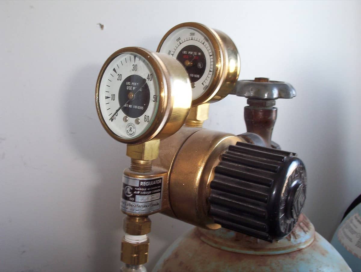 Close-up of a regulator valve and pressure gauge on a pipe